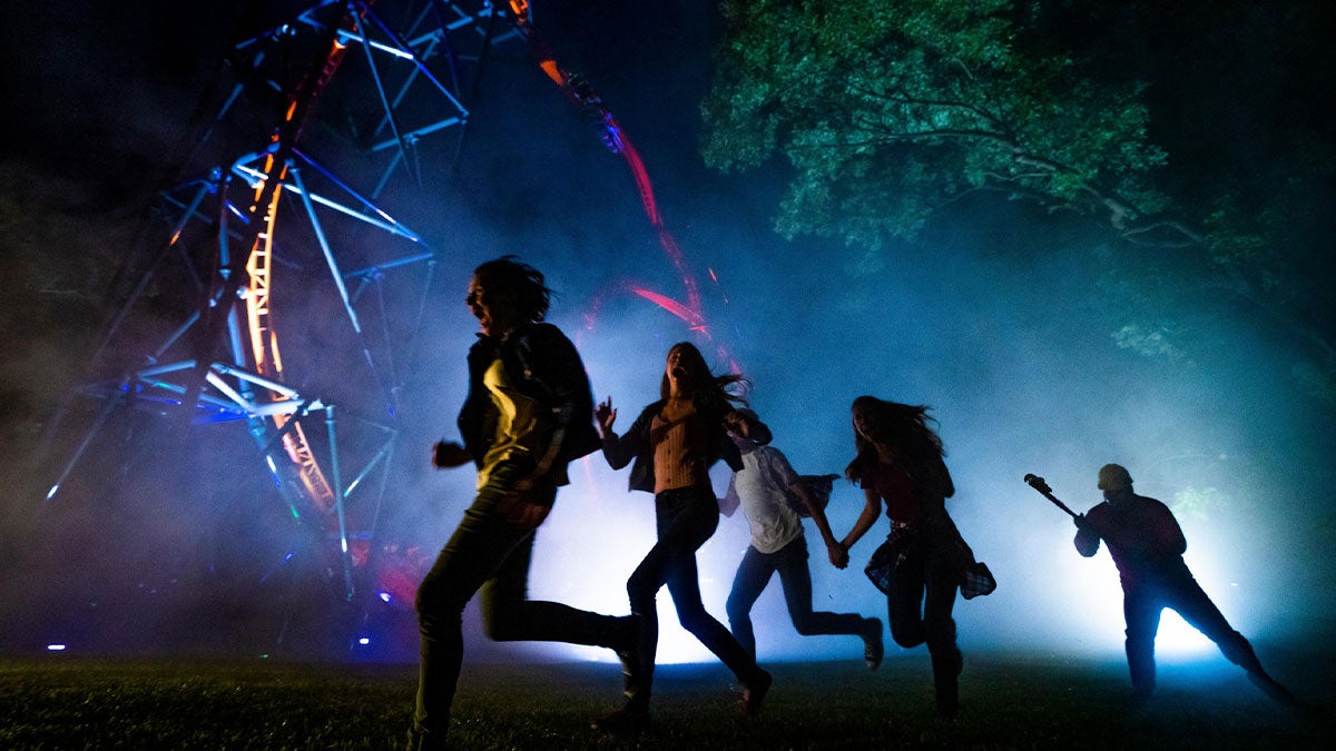 people running from character with ride and tree in the background at Howl-O-Scream busch gardens